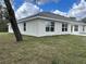 Stucco house and backyard with green and brown grass under a cloudy sky at 1010 Huntington St, North Port, FL 34288
