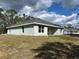 Rear view of the light green home, highlighting the backyard lawn and exterior architectural details at 5661 Gaffney Rd, North Port, FL 34286