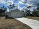Charming light green home with a two-car garage and long driveway set against a bright sky at 5661 Gaffney Rd, North Port, FL 34286