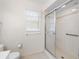 Clean bathroom featuring tiled shower with glass doors, a window with blinds, and accessible grab bar at 8993 Bantry Bay Blvd, Englewood, FL 34224