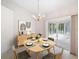 Dining room features a chandelier and sliding glass doors leading to a bright sunroom; digitally staged with mid-century furniture at 8993 Bantry Bay Blvd, Englewood, FL 34224