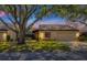 Tan one-story house with brown roof, large tree, and driveway at dusk at 3902 Glen Oaks Manor Dr, Sarasota, FL 34232