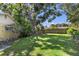 A grassy backyard featuring a large tree, a portion of a house, and a wooden fence in a tranquil setting at 2522 Fruit Tree Dr, Sarasota, FL 34239