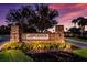 Esplanade at Artisan Lakes entrance sign surrounded by lush greenery under a dramatic sunset sky at 5510 Panella Ct, Palmetto, FL 34221
