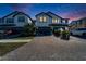 Evening view of two-story townhome with lights on and landscaping at 4564 Almada Ln, Wesley Chapel, FL 33543