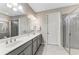 Elegant bathroom with double sinks, grey vanity, a large mirror, and a walk-in shower at 123 Pescador Pl, Nokomis, FL 34275