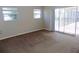 Bedroom featuring neutral carpet, two windows, and sliding glass door access to the pool area at 6555 Connecticut Ave, Sarasota, FL 34243