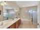 Primary bathroom with a double vanity, soaking tub, walk-in shower, and arched window at 2921 Seasons Blvd, Sarasota, FL 34240