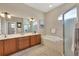 Primary bathroom with a double vanity, soaking tub, walk-in shower, and arched window at 2921 Seasons Blvd, Sarasota, FL 34240