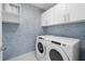 Well-lit laundry room featuring a modern washer and dryer with overhead cabinets at 111 S Pineapple Ave # 613, Sarasota, FL 34236