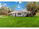 White single-story home with a manicured lawn and mature trees at 5246 Bay Shore Rd, Sarasota, FL 34234