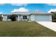 Single-story home with light gray exterior, two-car garage, and landscaped lawn at 2415 Ancient Rd, North Port, FL 34286