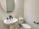 Small bathroom with pedestal sink, toilet, and oval mirror at 2528 Star Apple Way, Sarasota, FL 34240