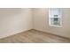 Bright bedroom with neutral walls and wood-look tile flooring, featuring one window at 2528 Star Apple Way, Sarasota, FL 34240