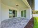 View of covered patio with stone flooring, white pillars, and sliding glass doors at 1010 Acadia Rd, Venice, FL 34293