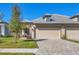 Tan two-car garage villa with paved driveway and landscaped lawn at 17890 Cherished Loop, Bradenton, FL 34211