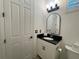 Clean half-bathroom featuring a modern vanity with black countertop, toilet, and stylish lighting at 15618 Castle Park Ter, Lakewood Ranch, FL 34202