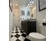 A sleek bathroom featuring a black and white tile floor, granite countertop, and stylish vanity at 15618 Castle Park Ter, Lakewood Ranch, FL 34202