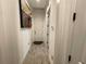 Hallway with elegant, neutral tile flooring and decorative wall art leading to a doorway at 15618 Castle Park Ter, Lakewood Ranch, FL 34202