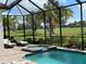 Enclosed pool and spa overlooking a well-manicured golf course with several lounge chairs on the brick patio at 15618 Castle Park Ter, Lakewood Ranch, FL 34202