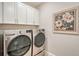 Laundry room with LG washer and dryer, upper cabinets and art at 18122 Harwich Pl, Bradenton, FL 34202