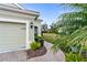 Landscaped walkway leading to a light green house with a garage at 5450 Fairfield Blvd, Bradenton, FL 34203