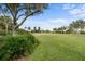 Landscaped yard with lush greenery, mature trees, and a distant house at 8480 Big Buck Ln, Sarasota, FL 34240