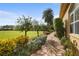 Stone pathway winds through lush landscaping, leading to a spacious grassy backyard at 8480 Big Buck Ln, Sarasota, FL 34240