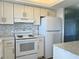 Bright kitchen with white cabinets, stone countertops, and a smooth top stove at 3993 Lake Bayshore Dr # F513, Bradenton, FL 34205