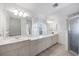 Bright primary bathroom features double vanity sinks, modern lighting, a shower, and white tile floors at 611 Mobile Rd, Venice, FL 34293