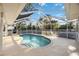 This is an in-ground screened pool with a unique design, surrounded by a stamped concrete deck and lush landscaping at 611 Mobile Rd, Venice, FL 34293