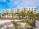 Modern beachfront building with palm trees and white sand at 915 Seaside Dr # 407, Sarasota, FL 34242