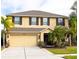 Two-story house with tan exterior, dark brown shutters, and palm trees at 4010 91St E Ave, Parrish, FL 34219