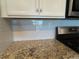 Modern kitchen features granite countertops and light gray glass backsplash at 2532 Avolet Ct, Lakewood Ranch, FL 34211