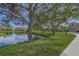 Houses along a pond with mature trees and a sidewalk at 4028 Mira Lago Dr, Sarasota, FL 34238