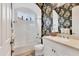 Bright bathroom with a shower-tub, white vanity, floral wallpaper, and a window with views of the outside at 12240 Thornhill Ct, Lakewood Ranch, FL 34202