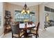 Cozy dining area features an elegant chandelier, a wood table, and a large window view of the pool at 12240 Thornhill Ct, Lakewood Ranch, FL 34202