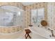 Bright bathroom with a soaking tub, separate shower, and decorative wallpaper at 12240 Thornhill Ct, Lakewood Ranch, FL 34202