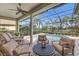 A covered patio with comfortable seating overlooks a screened-in pool and a view of the lake at 12240 Thornhill Ct, Lakewood Ranch, FL 34202