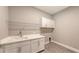 Bright laundry room with white cabinets, a utility sink, and ample shelving at 21205 Holmes Cir, Venice, FL 34293