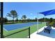 Well-maintained tennis court with shaded seating area at 21205 Holmes Cir, Venice, FL 34293