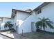 Condo building featuring a white facade, staircase entry, and well-maintained landscaping with palm trees at 4234 Gulf Of Mexico Dr # Y2, Longboat Key, FL 34228