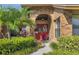 Inviting front entrance with a bright red double door and lush tropical landscaping at 4918 Fallcrest Cir, Sarasota, FL 34233