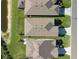 An overhead view of three houses with grey roofs and green lawns at 8721 Ocean Tides Cv, Parrish, FL 34219