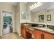 Double vanity with granite counters, wood cabinets, a large mirror, and views to the bedroom at 340 Cedar Falls Dr, Apollo Beach, FL 33572