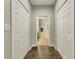 Hallway with hardwood floors and view of bathroom, flanked by white bi-fold closet doors at 340 Cedar Falls Dr, Apollo Beach, FL 33572