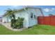 Charming home featuring a well-maintained lawn, vibrant flower beds, and a colorful red fence for added curb appeal at 1080 Piedmont Rd, Venice, FL 34293