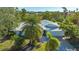 An eye-level view of a single-story home with a metal roof, lush landscaping, and a paved driveway at 435 Partridge Cir, Sarasota, FL 34236