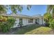 Exterior view of the home featuring lush landscaping, a metal roof, and blue entry door at 435 Partridge Cir, Sarasota, FL 34236