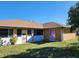 Rear house view, showing a light yellow stucco exterior, and a grassy backyard at 25692 Aysen Dr, Punta Gorda, FL 33983